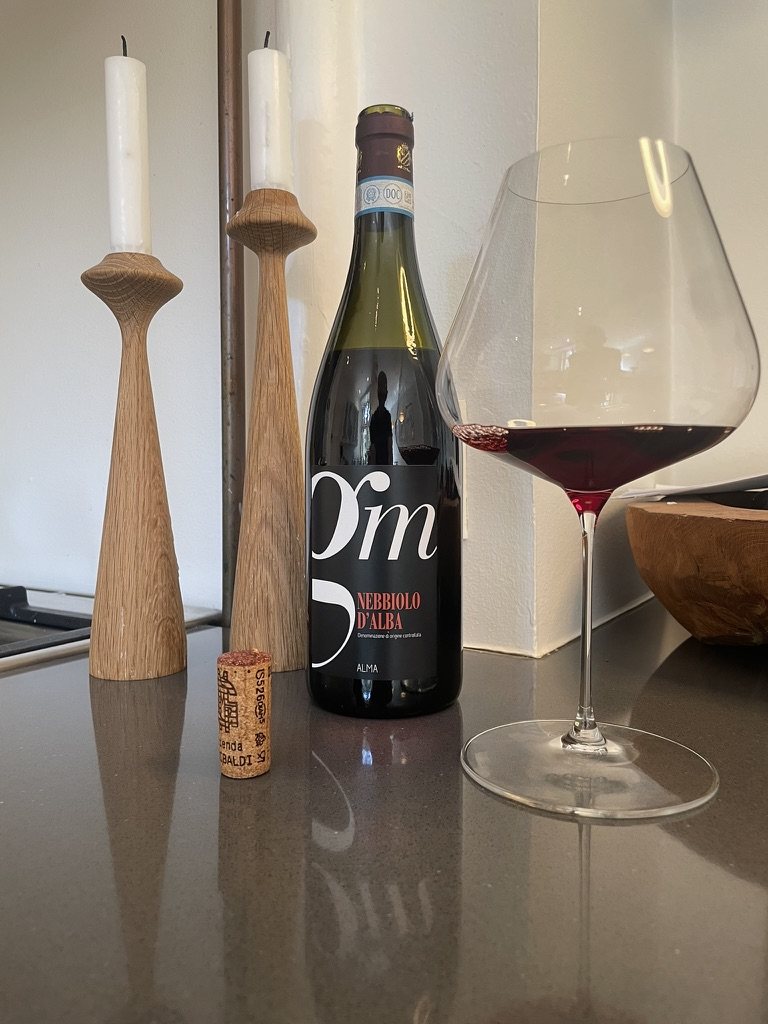Flaske Nebbiolo d&rsquo;Alba fra AL-MA med prop og fyldt glas p&aring; en k&oslash;kkenbordplade